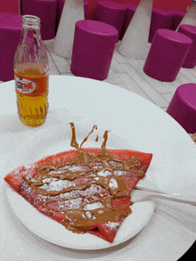 a bottle of fanta sits next to a plate of food on a table