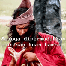 a man in a red robe is holding a sword with the words " semoga dipermudahkan urusan tuan hamba " below him