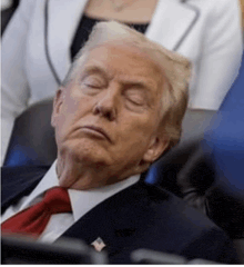donald trump is sleeping in a chair with his eyes closed while wearing a suit and tie .