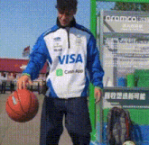 a man holding a basketball wearing a visa jacket