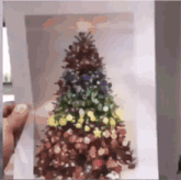 a person is holding a picture of a christmas tree on a piece of paper