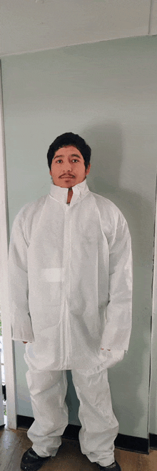 a man wearing a white coverall stands in front of a door