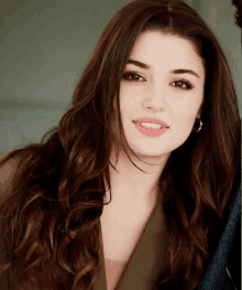 a close up of a woman 's face with long brown hair and earrings .