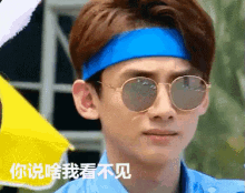 a young man wearing sunglasses and a blue headband has chinese writing on his face