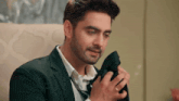 a man in a suit and tie is sitting on a couch and holding a pair of shoes .