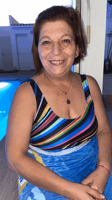 a woman wearing a colorful striped top and a blue towel smiles for the camera