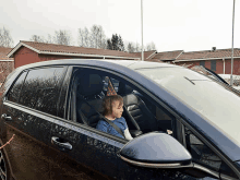 a young boy wearing a birthday hat sits in a car