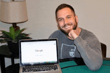 a man sitting in front of a laptop that says google on it