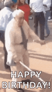 an elderly man is walking with a cane in a crowd of people and says `` happy birthday '' .