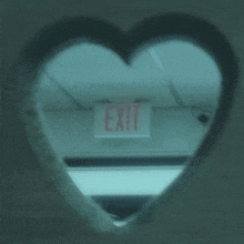 a heart shaped hole in a wall with a red exit sign above it