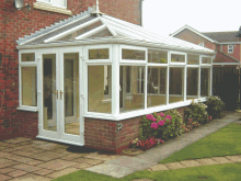 a brick house with a white conservatory with a glass roof