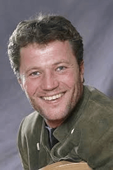a man with a beard is smiling for the camera while wearing a green jacket .