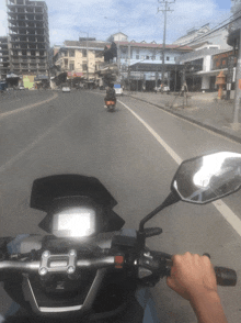 a person riding a motorcycle down a street with a building in the background that says ' a ' on it