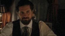 a man with a beard wearing a white shirt and black vest