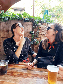 two women sit at a table with a plastic cup of beer and a bag that says ' texas ' on it