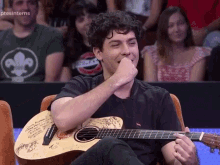 a man sitting in front of a crowd holding a guitar with signatures on it and the words pts interns on the bottom