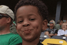 a young boy making a funny face while sitting in a crowd of people