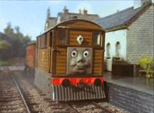 a train with a face on the front of it is on the tracks