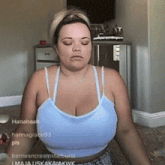 a woman in a blue tank top is sitting on the floor with her eyes closed
