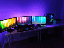 three computer monitors are on a desk with a purple background