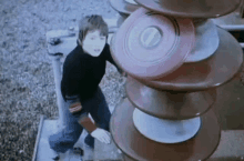 a boy standing in front of a stack of plates with the letter t on it