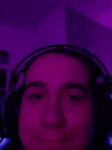 a close up of a person wearing headphones with purple lights behind them