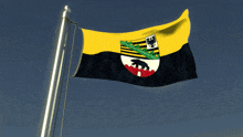 a yellow and black flag with a bear on it is flying in the wind