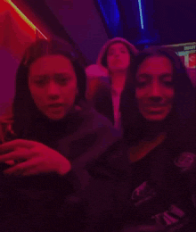 a group of girls are standing next to each other in a room with red lights