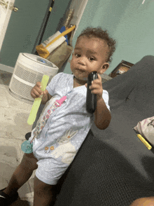 a baby with a pacifier in his mouth is holding a cell phone