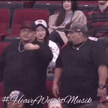 a group of people are sitting in a stadium watching a game and a woman is waving her hand in the air .