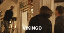 a man standing on a ladder in front of a building with the word vikingo on the bottom