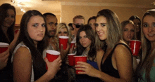 a group of people are holding red cups and making faces