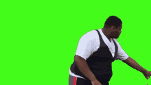 a man in a white shirt and black vest is standing in front of a green screen .