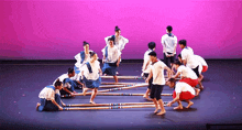 a group of people dancing on a stage with a pink backdrop