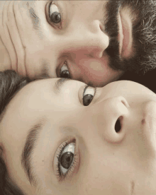 a man with a beard and a child with their eyes looking at the camera