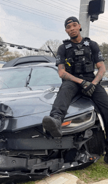 a police officer is sitting on the hood of a damaged car