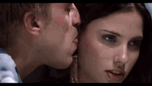 a man is kissing a woman on the cheek in a close up of a movie scene .