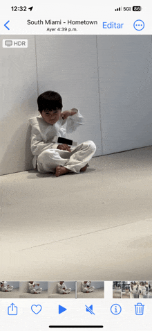 a phone screen shows a picture of a young boy sitting on the floor