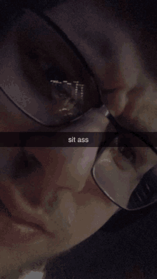 a close up of a person 's face with glasses and the caption sit ass