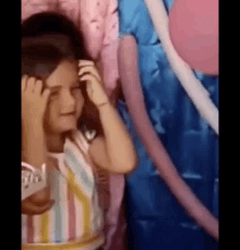 a little girl is standing in front of a pink and blue inflatable castle .