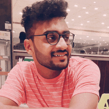 a man wearing glasses and a pink shirt is smiling in front of a fruit tea sign