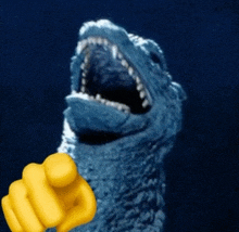 a blue monster with its mouth open and a yellow finger pointing at it