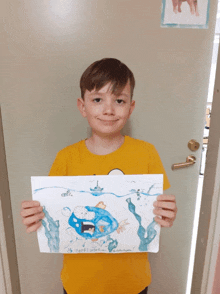 a young boy in a yellow shirt holds up a drawing of a polar bear