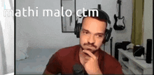 a man wearing headphones is sitting in front of a microphone with the words mathi malo ctm above him .