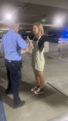 a woman in overalls is being searched by a police officer