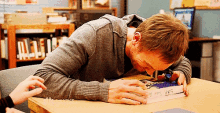 a man sits at a desk with his head on a book that has the word uss written on it