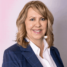 a woman wearing a blue jacket and white shirt smiles