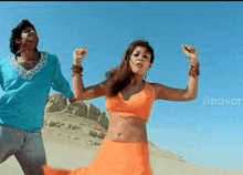 a man and a woman are dancing on a sandy beach .