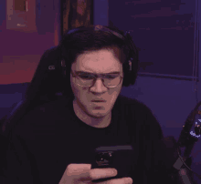 a man wearing glasses and headphones looking at his phone