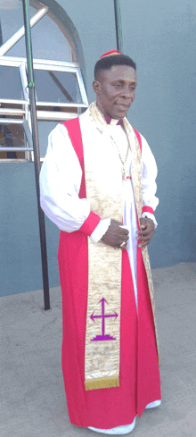 a man in a red robe has a purple cross embroidered on his sash